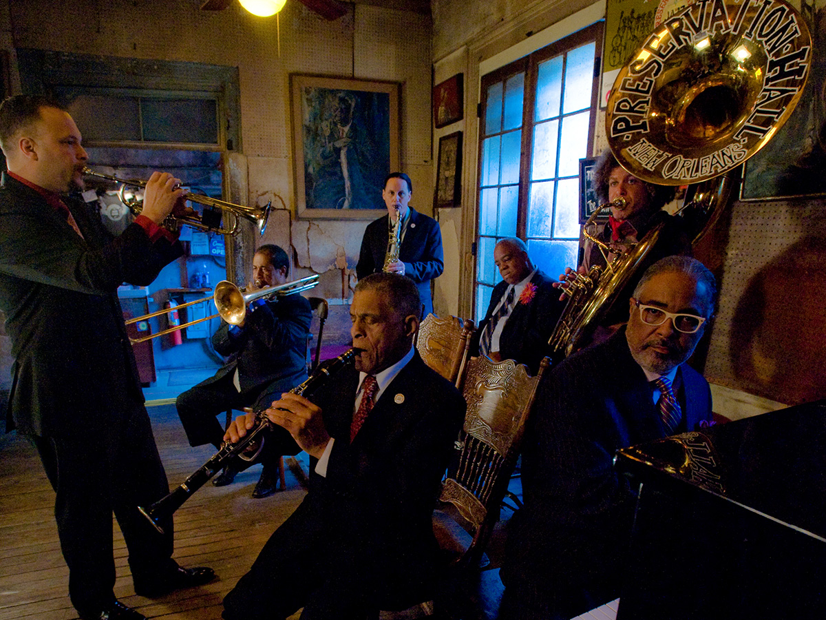 Preservation Hall Jazz Band in New Orleans Jazz musicians in formal suits performing with various instruments inside the Preservation Hall in New Orleans, Louisiana.