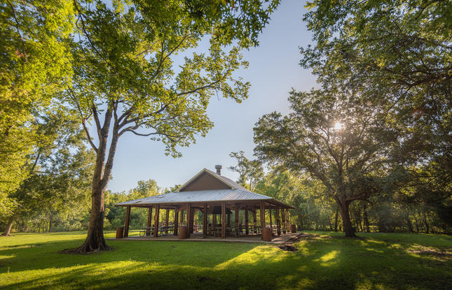 The group pavilion at St. Bernard State Park sits on a green, grassy hill, surrounded by trees.