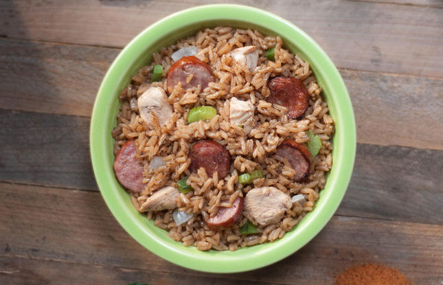 A green bowl of jambalaya, a rice dish made with chicken, sausage, onions, celery and more.