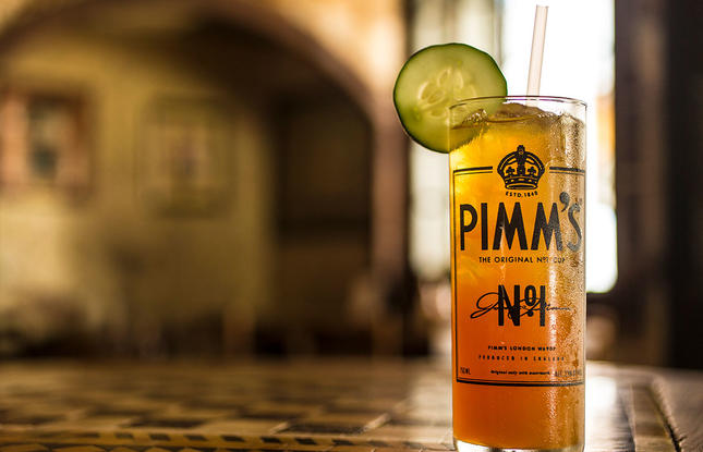 A vibrant orange cocktail, garnished with a cucumber slice, on a table at Napoleon House in New Orleans, Louisiana.
