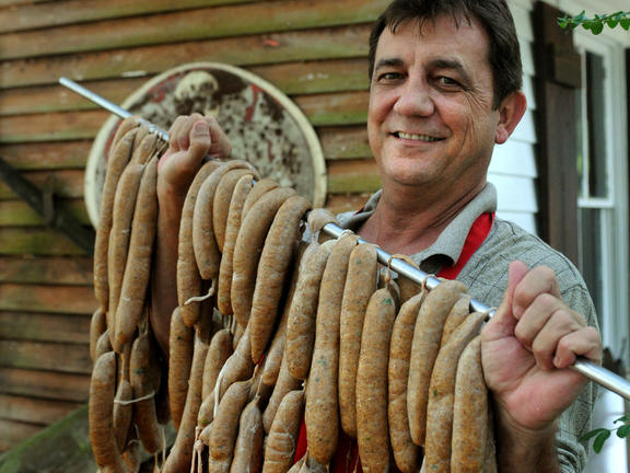 Man smiling and holding strings of Boudin sausages
