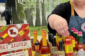A woman reaches across a display of Louisiana hot sauces, which includes TABASCO, Louisiana brand and others.