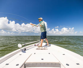 A man casts his line off the bow of a boat in the Gulf.
