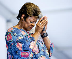 Irma Thomas folds her hands over her microphone in prayer at Jazz Fest.