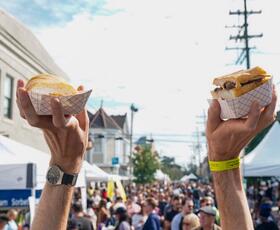 A visitor holds up po'boy sandwiches at Oak Street Po-Boy Festival.