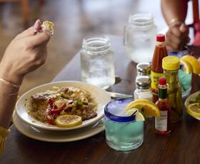 A table filled with Cajun and Creole dishes, hot sauces, spices and beverages at Orlandeaux’s Cafe.