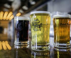 Three beers of varying shades atop a table at Great Raft Brewing.