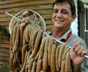 Man smiling and holding strings of Boudin sausages