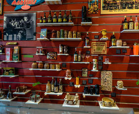 A red wall holds several shelves, each filled with bottles of all shapes, sizes and colors