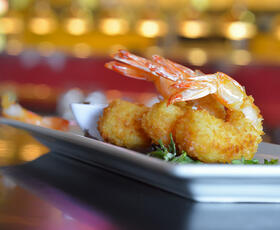 Three pieces of fried coconut shrimp on a white plate